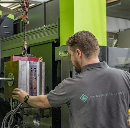 Skilled employee at work with the injection molding machine at De Beer Group